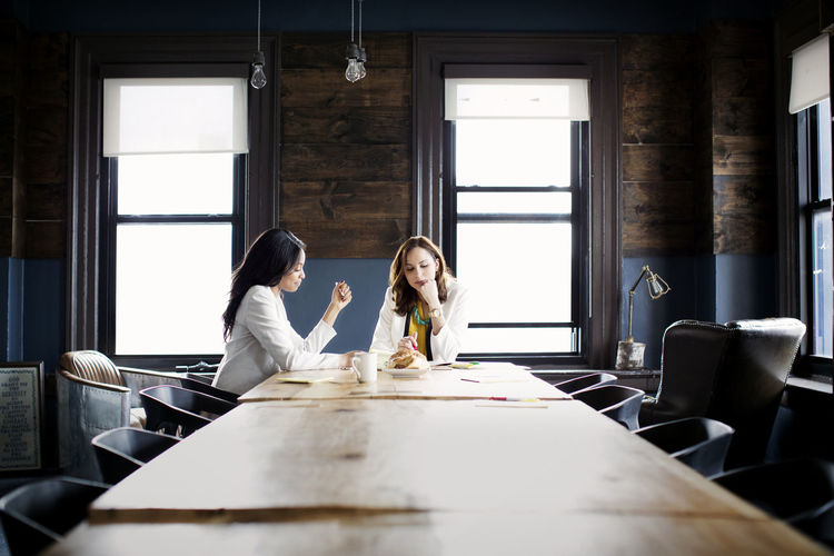 Businesswomen discussing while sitting at desk in office