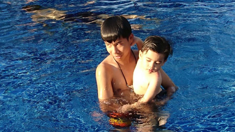 Shirtless teenage boy with brother in swimming pool