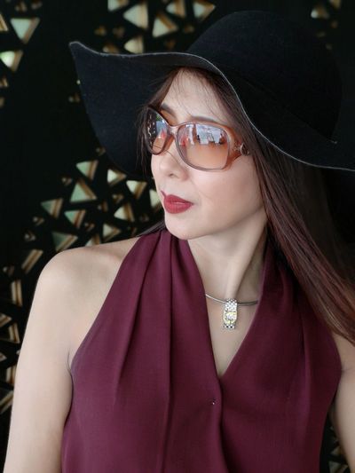 Fashionable woman wearing sunglasses and hat looking away