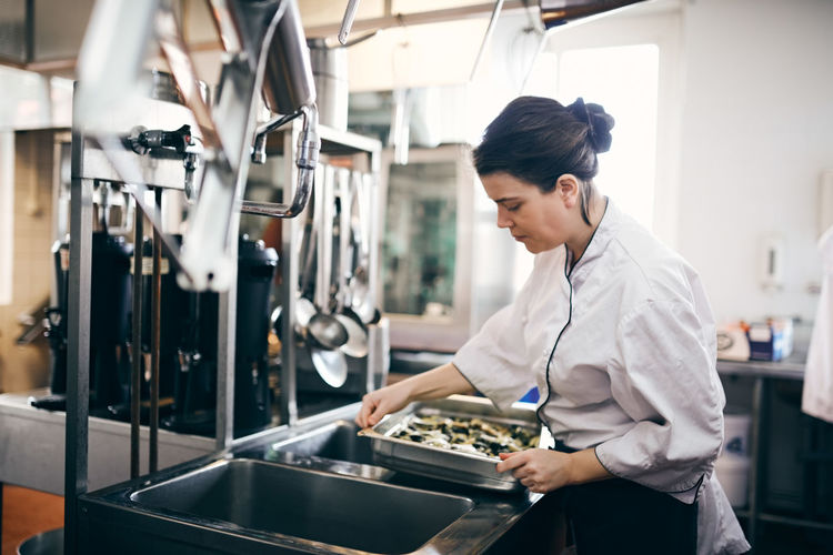 Mid adult female chef preparing food in commercial kitchen