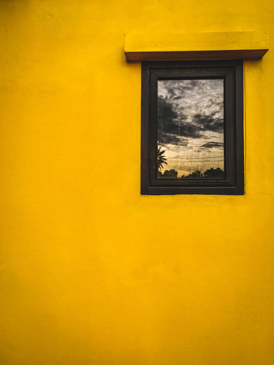 Low angle view of window on yellow wall