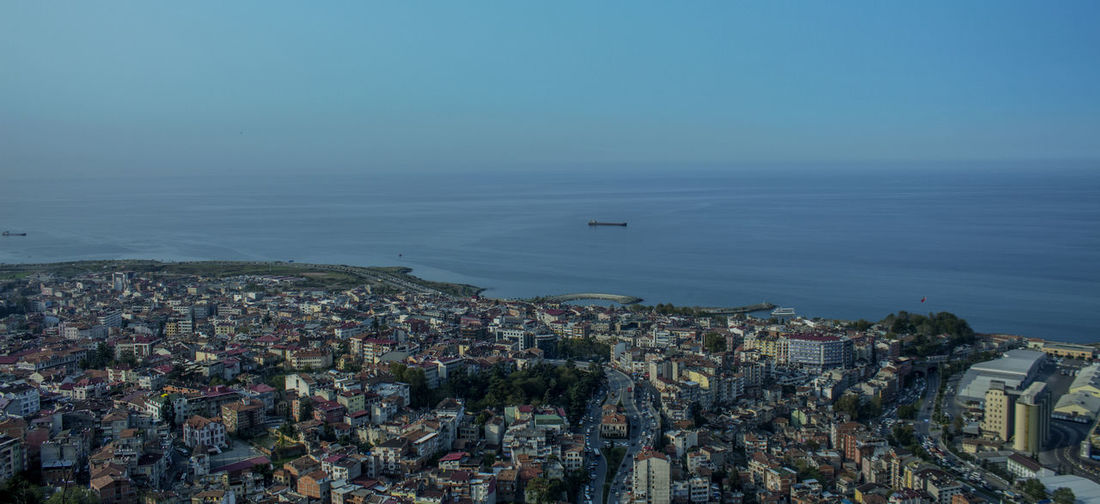 High angle view of cityscape by sea against clear sky