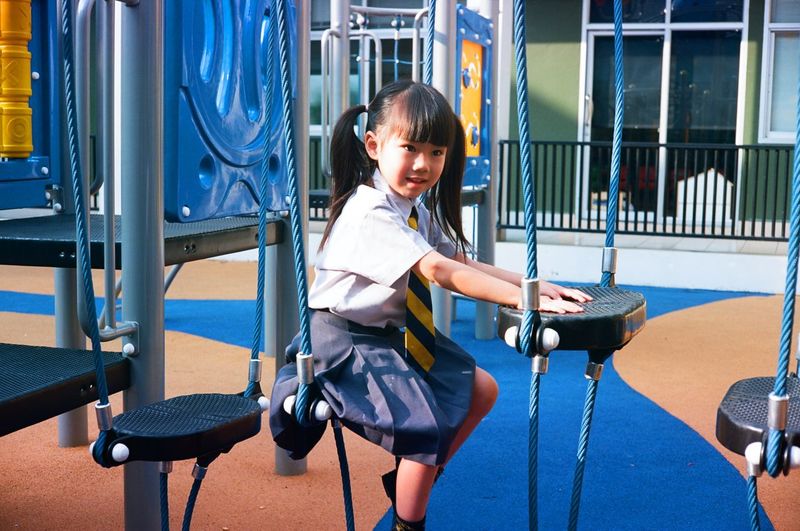 Smiling girl sitting on outdoor play equipment at playground