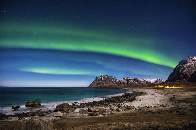 Scenic view of sea and mountains against sky at night