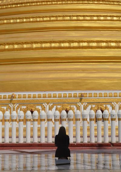 Rear view of woman praying while looking at mosque