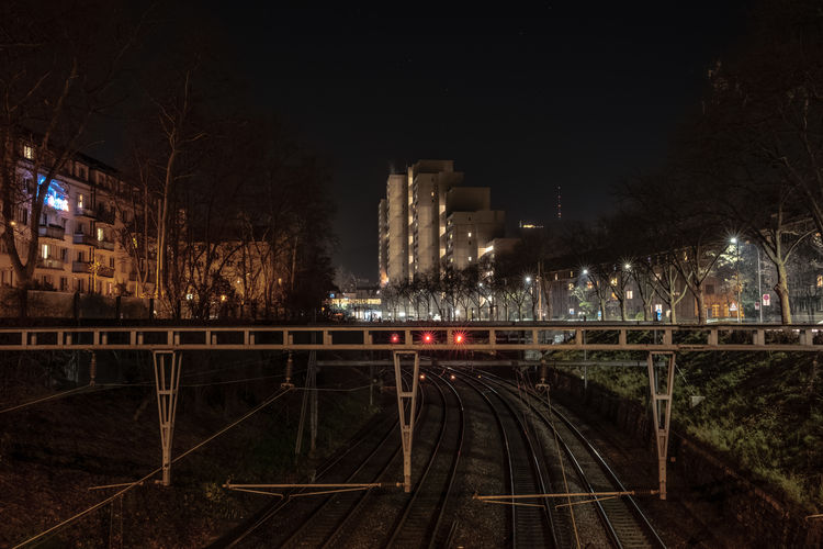 Railroad tracks amidst buildings in city at night