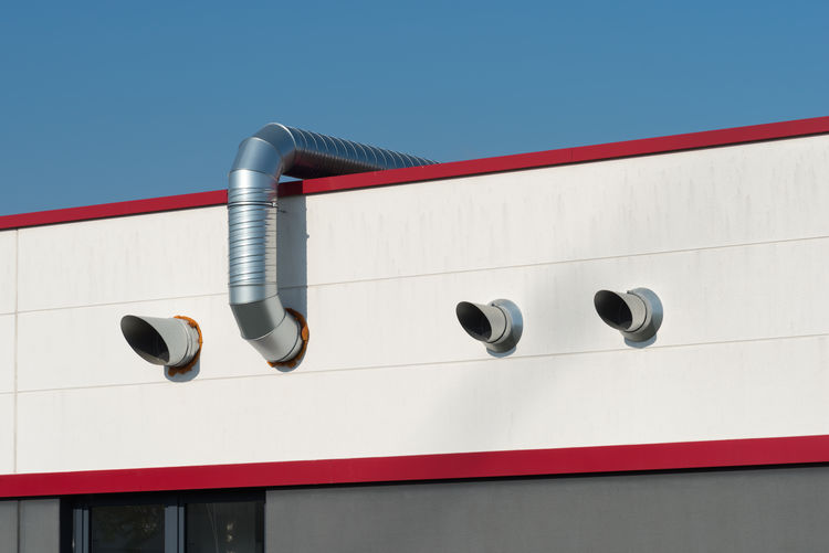 Stainless steel air ducts on a red roof with clear blue sky