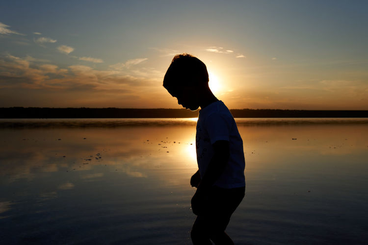 Child boy silhouette on the sunset time by the sea.