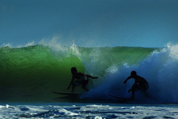 Silhouette men surfing in sea against sky