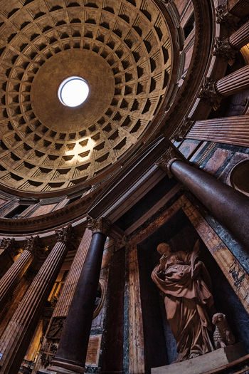 The dome of the pantheon in rome from inside, with light coming through the top opening.