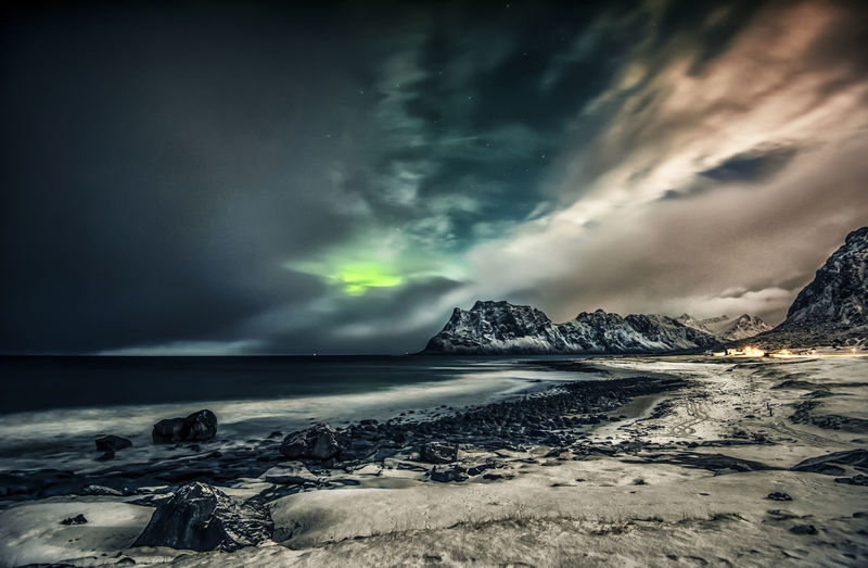 Scenic view of sea and mountains against storm clouds