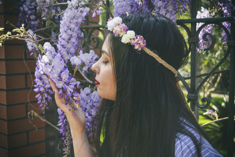 Close-up of woman smelling flowers on gate