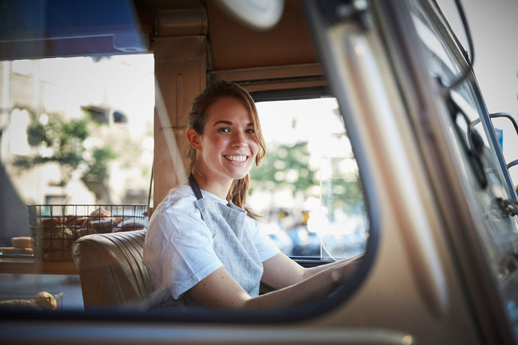 Portrait of smiling young female owner driving food truck in city