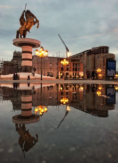 Reflection of illuminated buildings in puddle
