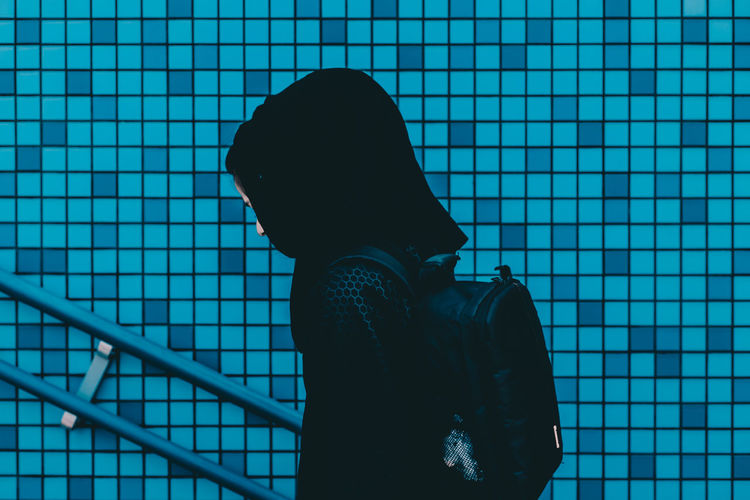 Low angle view of woman against blue tiled wall