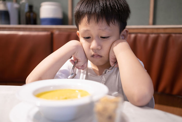 Portrait of cute boy with ice cream in bowl on table