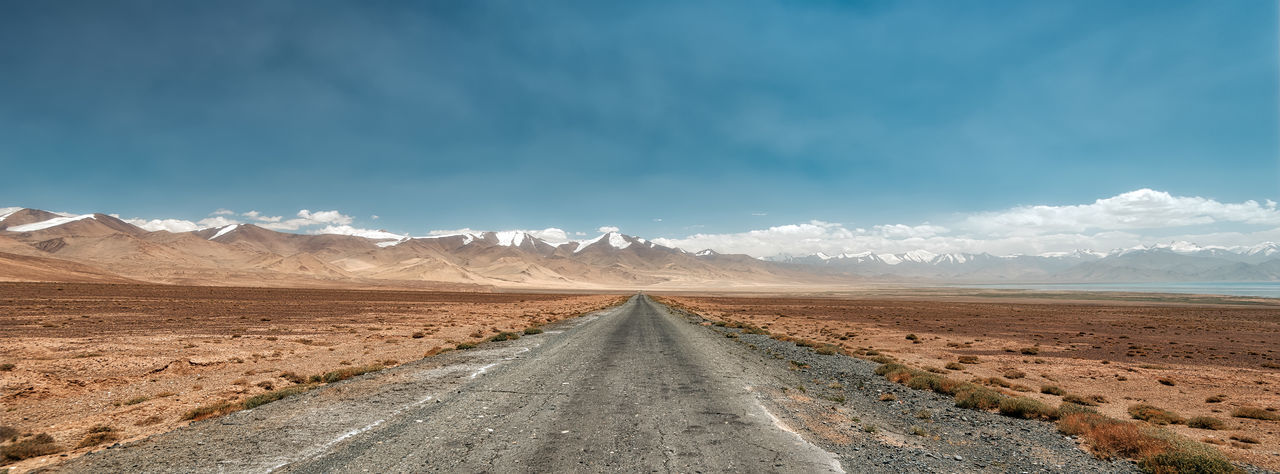Road leading towards mountains against sky