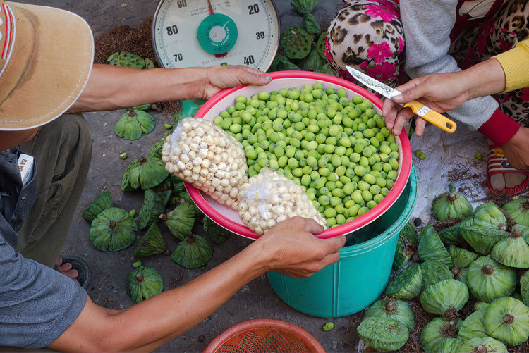 Lotus seeds for sale in local market. seller with knife to extract seeds. scales in background.