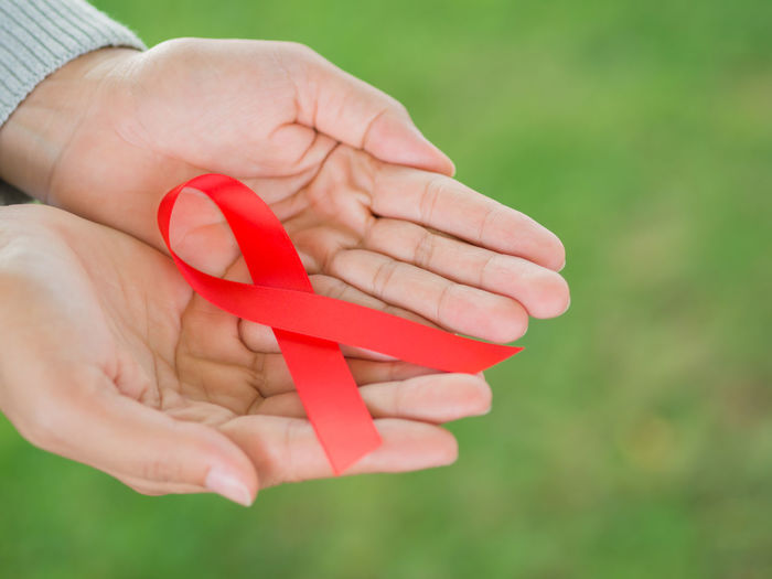 Cropped hand of woman holding aids awareness ribbon