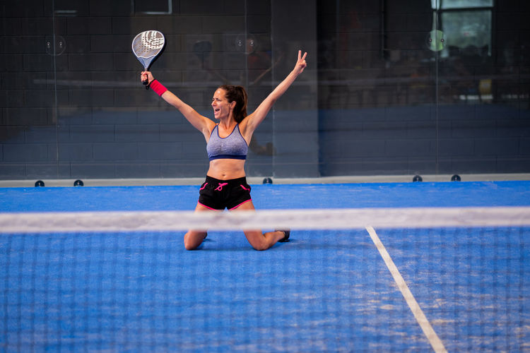 Portrait of beautiful young wimmer girl exulting on indoor padel tennis court