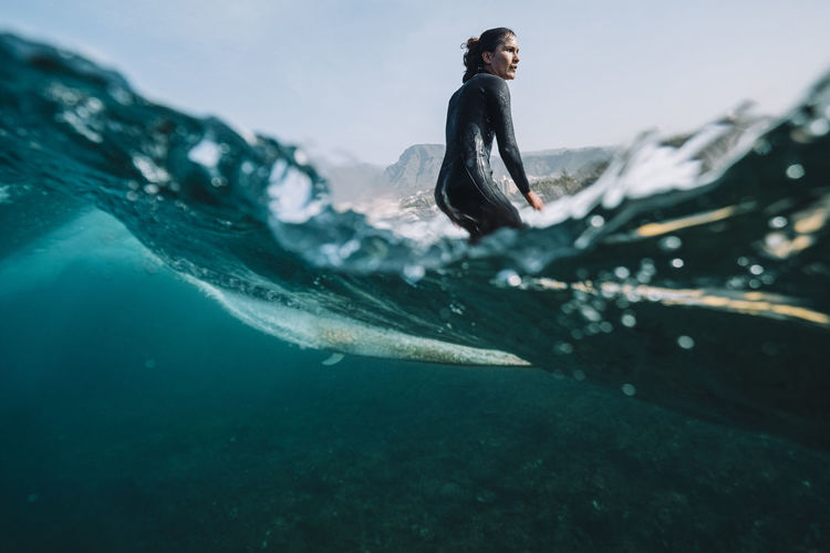 Split image of female surfer surfing a small wave