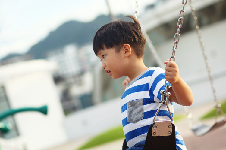 Side view of boy swinging at playground