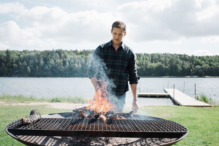 Full length of man standing on barbecue grill against sky