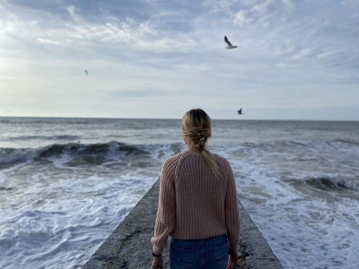 High angle view of a bird flying in the sky. girl looks at the sea and waves.seagulls fly in the sky