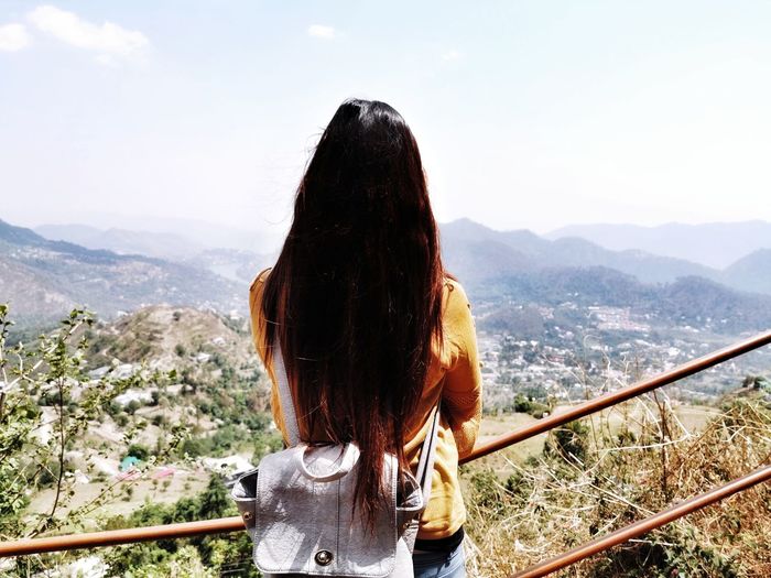 Rear view of woman looking at mountain against sky