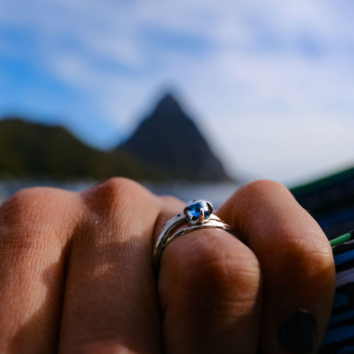 Cropped image of woman hand with ring against sky