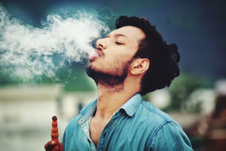 Young man smoking hookah outdoors