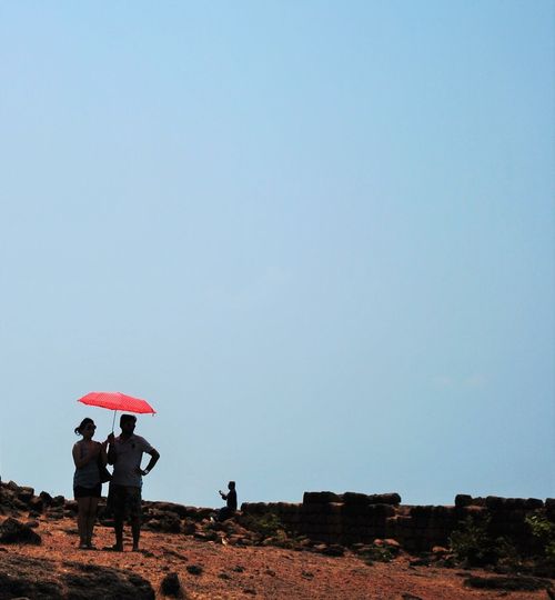 People standing under a red umbrella