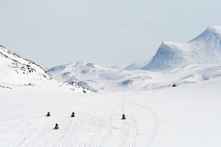 People on snowmobiles in mountains