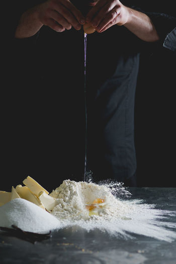 Cropped view of chef cracking egg onto flour