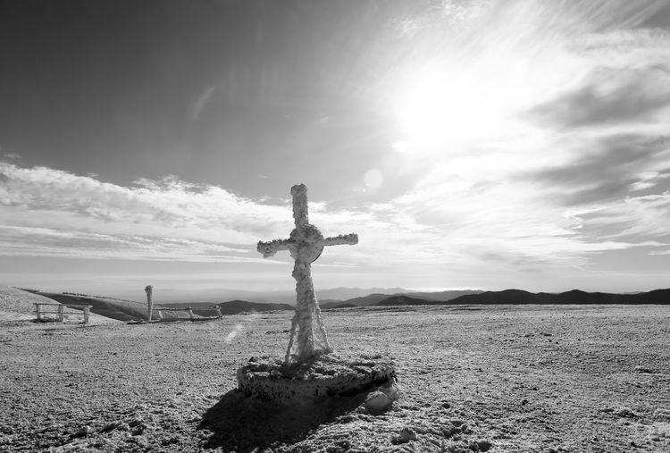 Cross on field against sky
