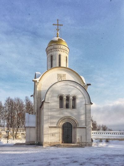 Church by building against sky during winter