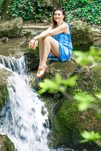 Portrait of young woman sitting on rock