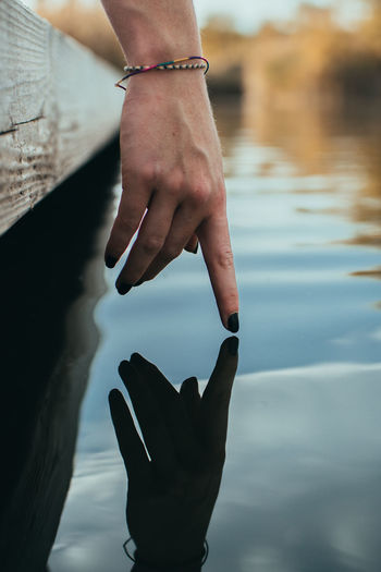 Cropped hand reflection on lake