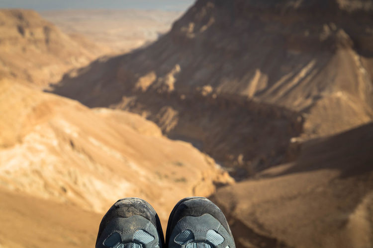 Low section of person shoes against rocky mountains