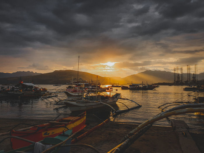 Boats moored at the beach during sunset