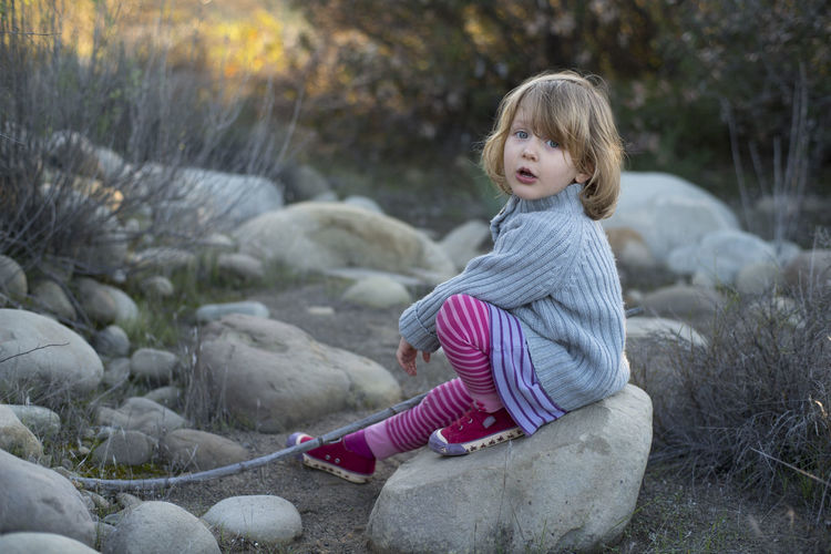 Portrait of girl sitting on rock