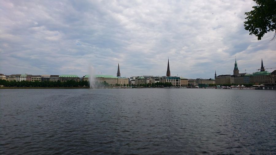 City at waterfront against cloudy sky