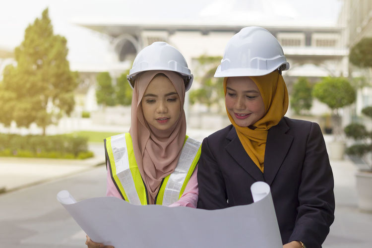 Female architects examining blueprint on street