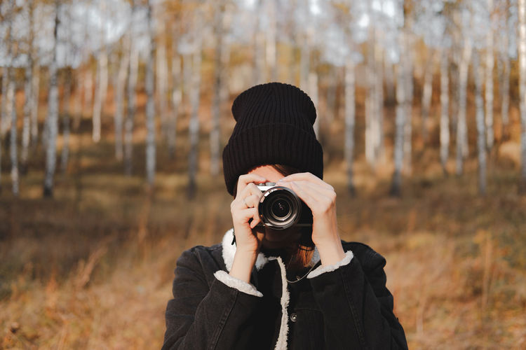 Portrait of a young woman with camera taking a picture in beauti