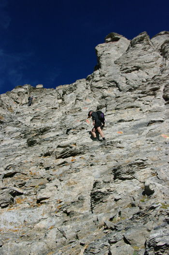 Low angle view of man climbing on cliff