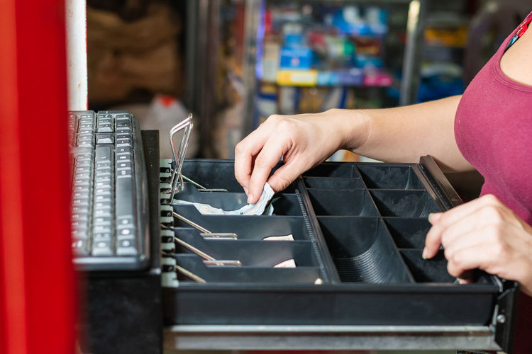 Hand of an enterprising latina woman in her business opening the cash register.