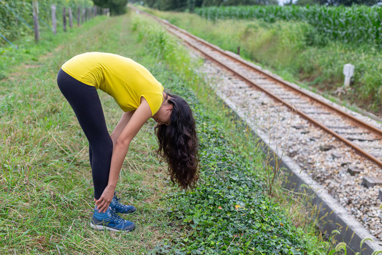 Rear view of woman exercising on railroad track
