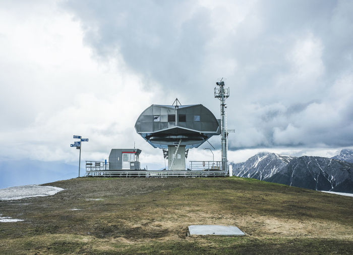 Ski lift station and mountains against cloudy sky