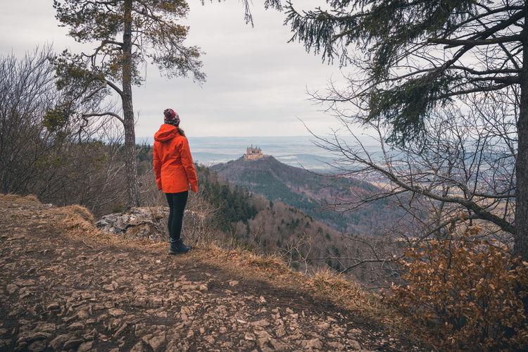 Rear view of woman standing on mountain against sky near burg hohenzollern, germany.