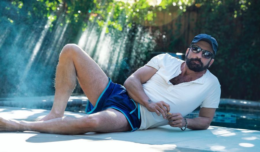 Man wearing sunglasses reclining at poolside